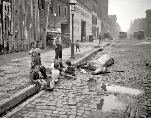 Impoverished children play next to a dead horse in London.